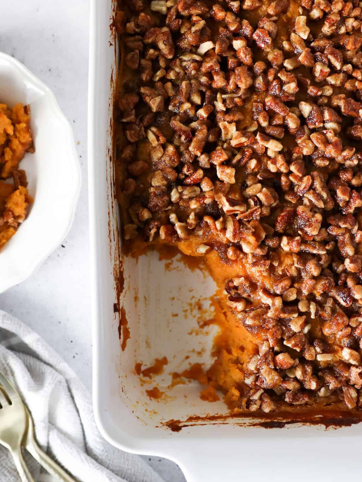 Overhead view of sweet potato casserole with some scooped out on a plate.