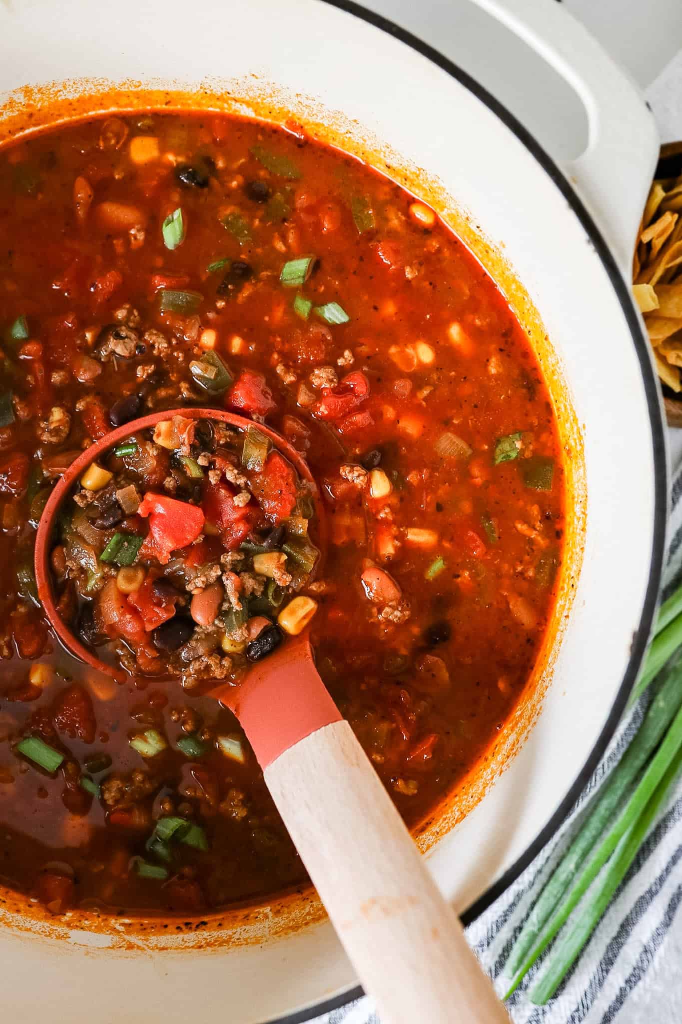 Overhead view of taco soup in a dutch oven with a ladle scooping some of the soup out.