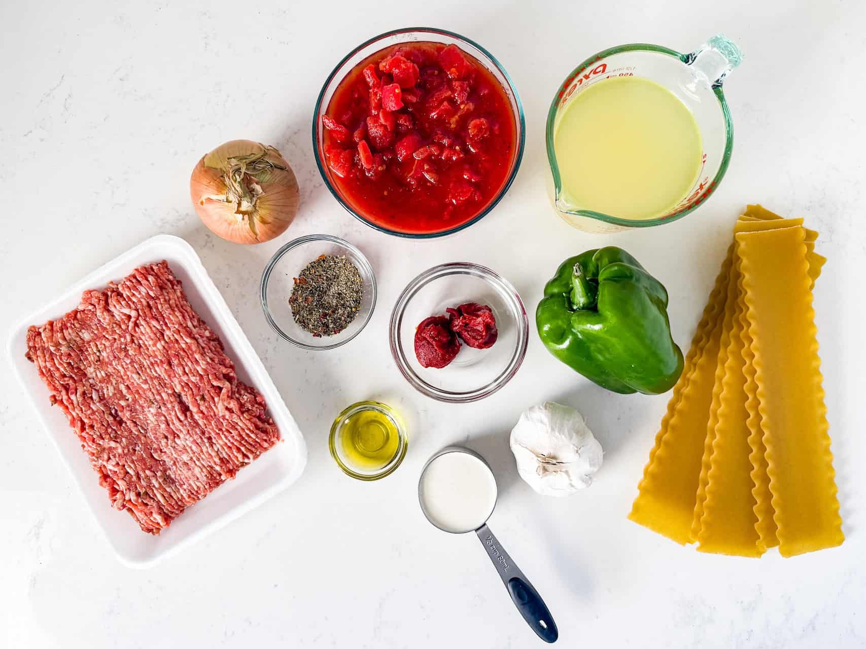 Overhead view of ingredients for lasagna soup on a white countertop.
