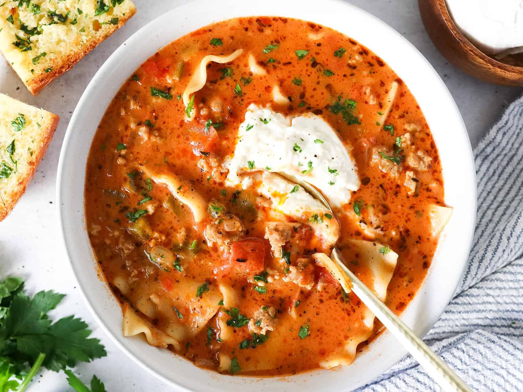 Overhead view of lasagna soup in a bowl with a spoon scooping some out.