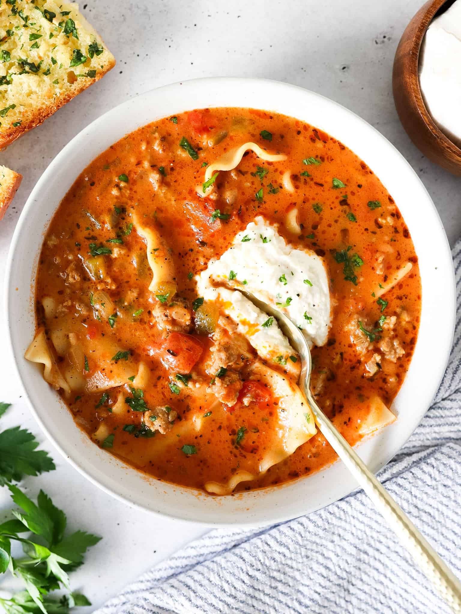 Overhead view of lasagna soup in a bowl with a spoon scooping some out.